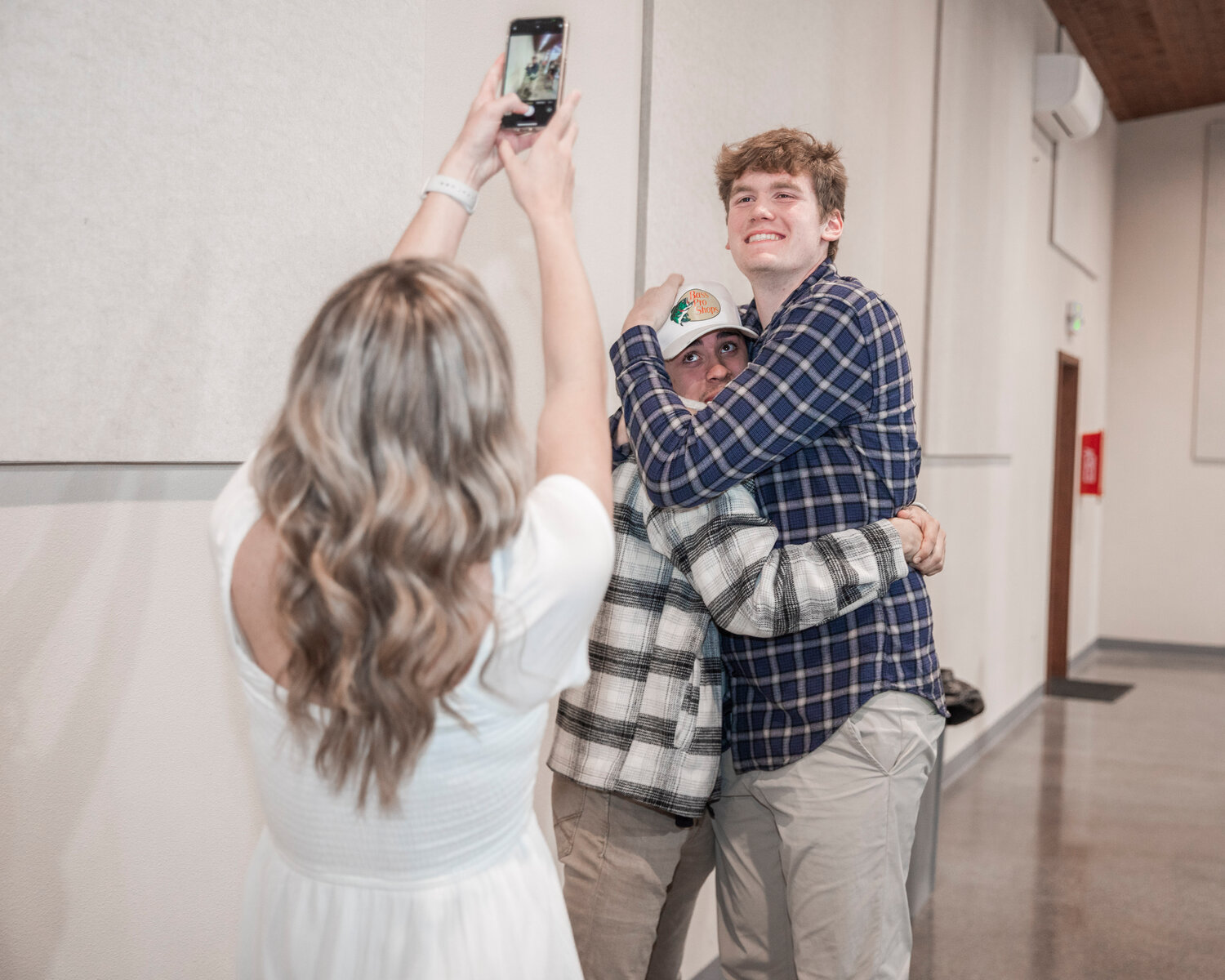 Cameron Sheets stretches up as Soren Dalan smiles for a photo while hugging Gabe Cuestas Tuesday evening during the “Athletes of the Year” banquet at the Jester Auto Museum.