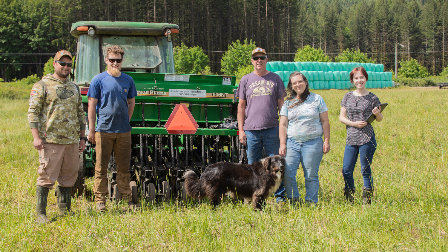From left, Veterans Conservation Corps Intern Chris Volmert, fourth-generation dairy farmer Jack Mallonee and his father Maynard Mallonee, English shepherd Turbo, Lewis Conservation District Special Projects Coordinator Kelly Verd, and Outreach Coordinator Kenna Fosnacht pose for a photo in front of a no-till seed driller available for a limited time at $5 per acre.