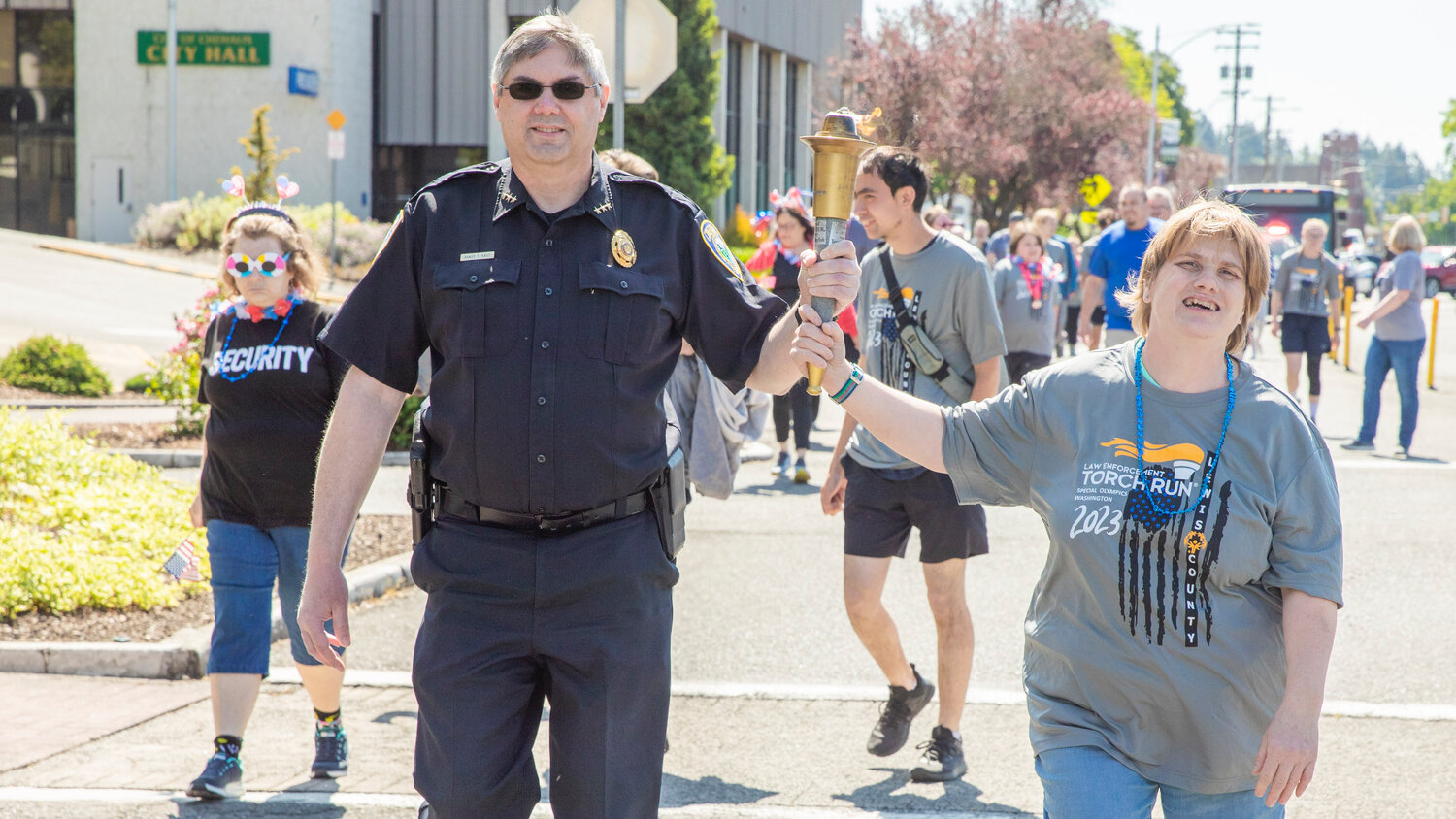 Chehalis Police Chief Randy Kaut holds the torch with participants in the Lewis County Special Olympics Law Enforcement Torch Run on Friday, June 2.