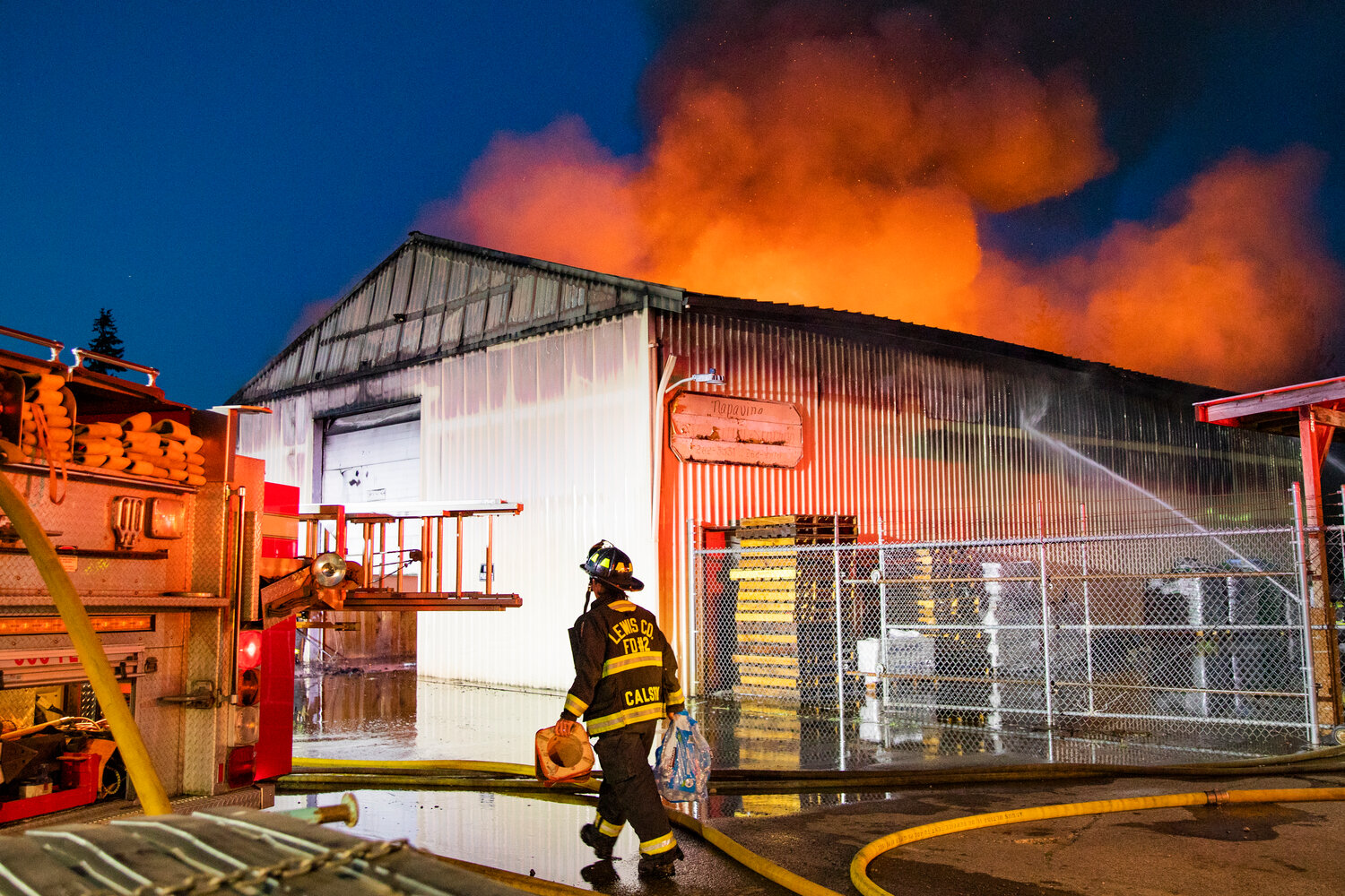 Firefighters are supplied with water bottles as they fight a blaze in an aluminum storage building in Napavine on Saturday, June 3.