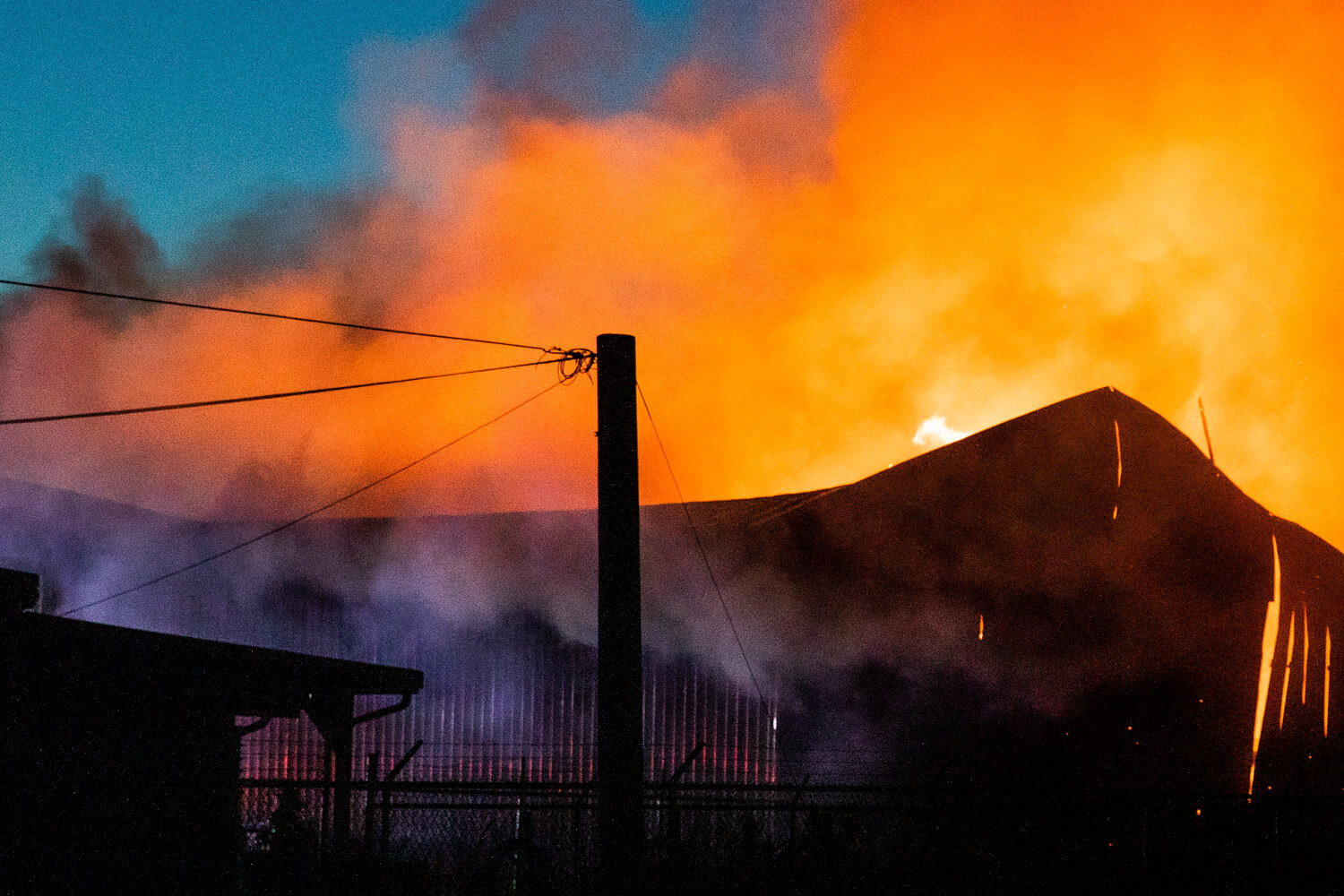 Flames inside a storage building in Napavine on Saturday night threaten to push out the east-facing aluminum wall of the building behind Ace Hardware while firefighters battle back the blaze.