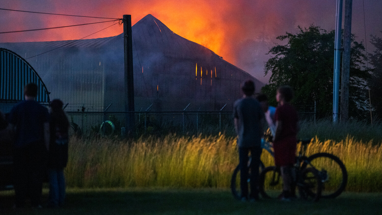 Kids watch as firefighters battle flames inside a structure near the 100 Block of Alder Avenue Northwest in Napavine on Saturday, June 3.