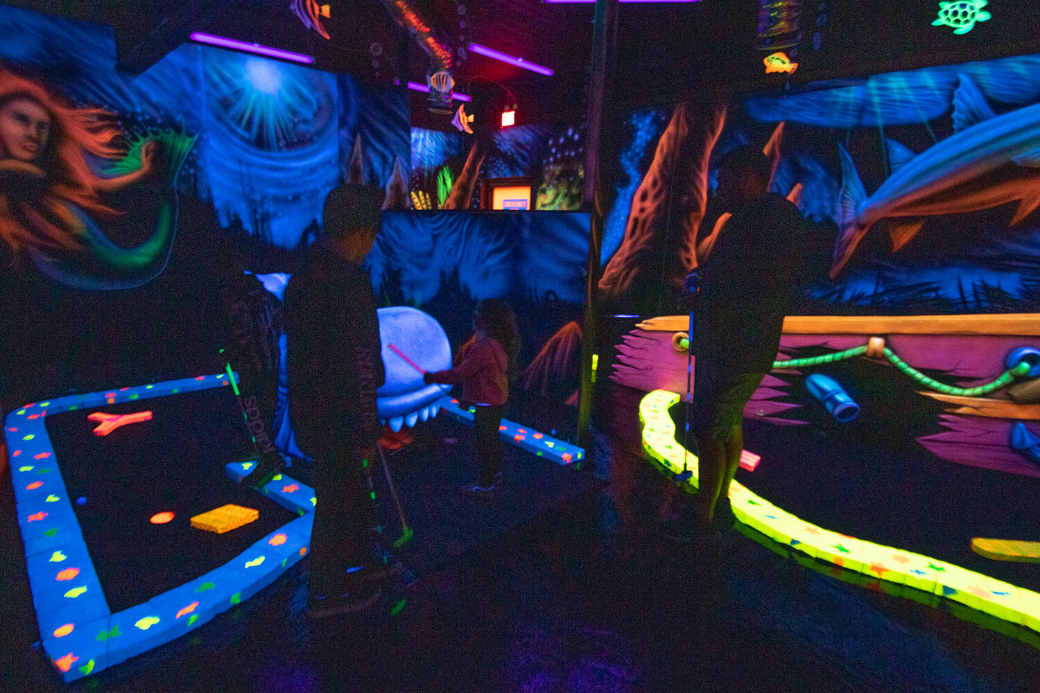 A family enjoys a round of black light mini golf at Shankz, which reopened on Aug. 20 after being forced to move from its old location at the Yard Birds mall last November.