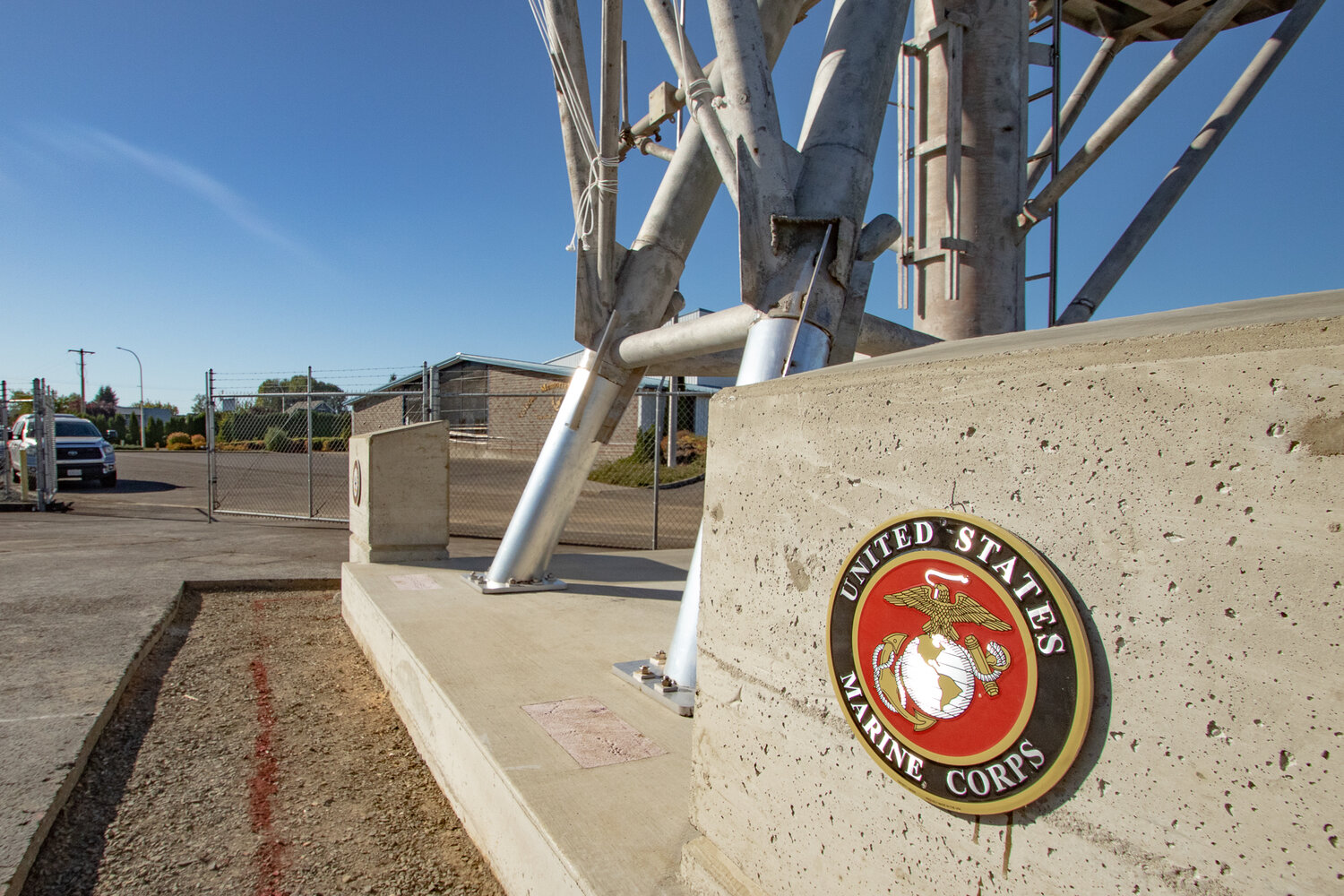 The U.S. Marine Corps logo sits mounted on one of two concrete encased containers for visitors to put coins in following a naval tradition known as mast stepping, where coins are placed under a mast before it's mounted on a ship and is thought to bring good luck. It is believed the tradition originated in ancient Rome when sea travel was dangerous, and the coins were placed to ensure sailors would be able to cross into the afterlife if the ship was sunk.