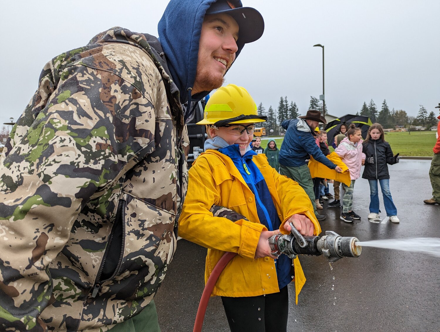 Students smile while using a fire hose outside Orin C. Smith Elementary in Chehalis.