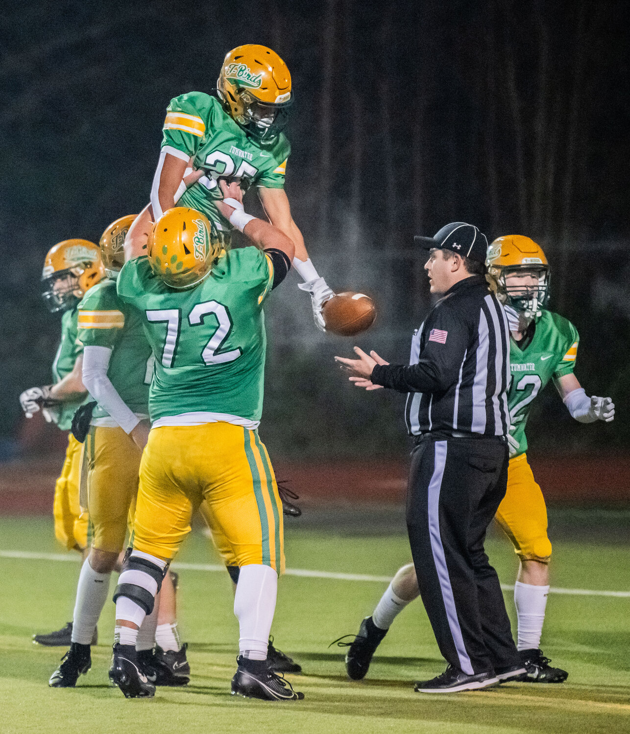 Tumwater’s Kooper Clark (35) is hoisted into the air in celebration after he scored a touchdown for the Thunderbirds in a 2A state semifinal game against North Kitsap on Saturday night.