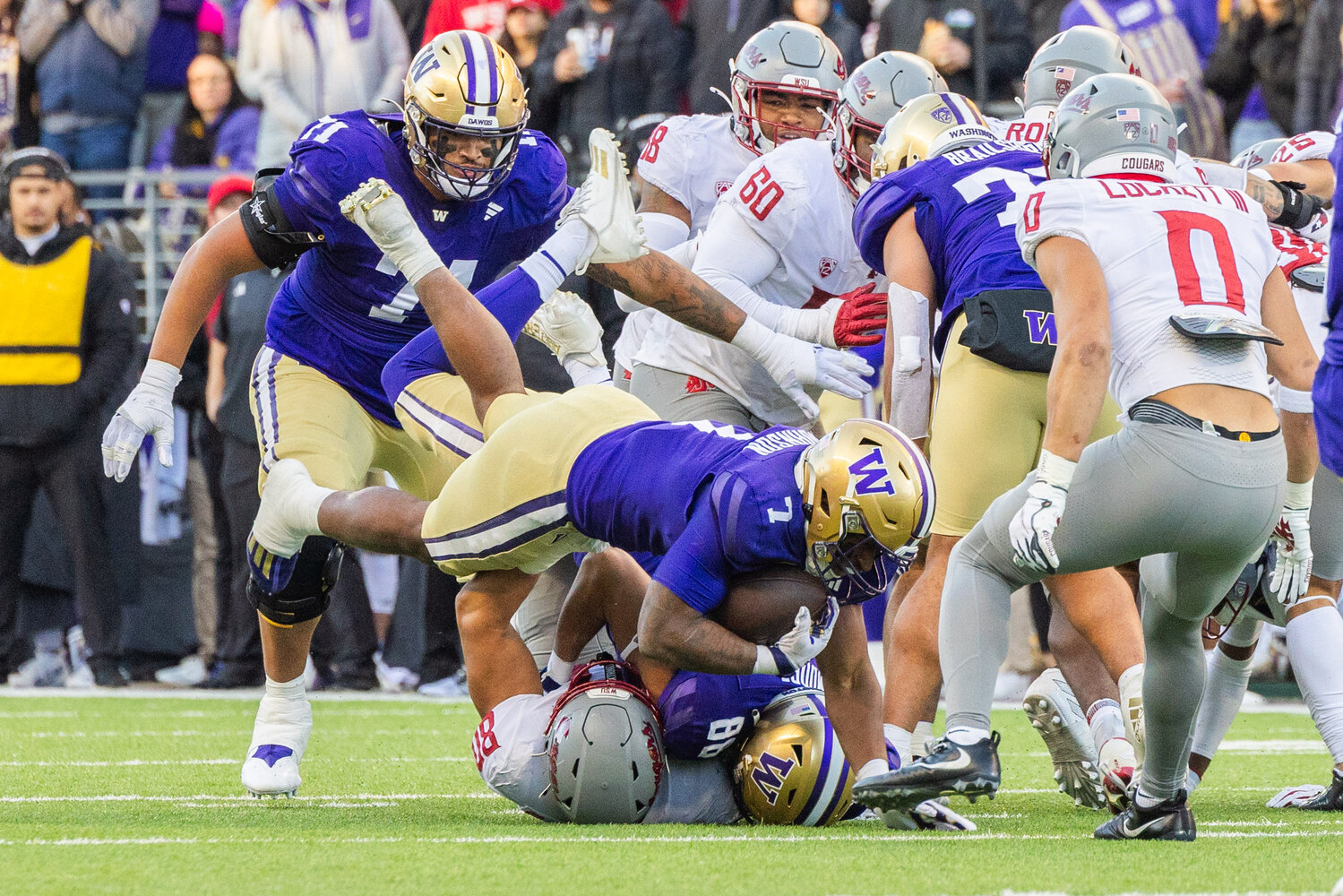 Huskies running back Dillon Johnson (7) looks fro extra yards as he is brought down by Cougars defender Brennan Jackson (80) during the Boeing Apple Cup Series football game in Seattle against the Washington State University Cougars on Saturday, Nov. 25.