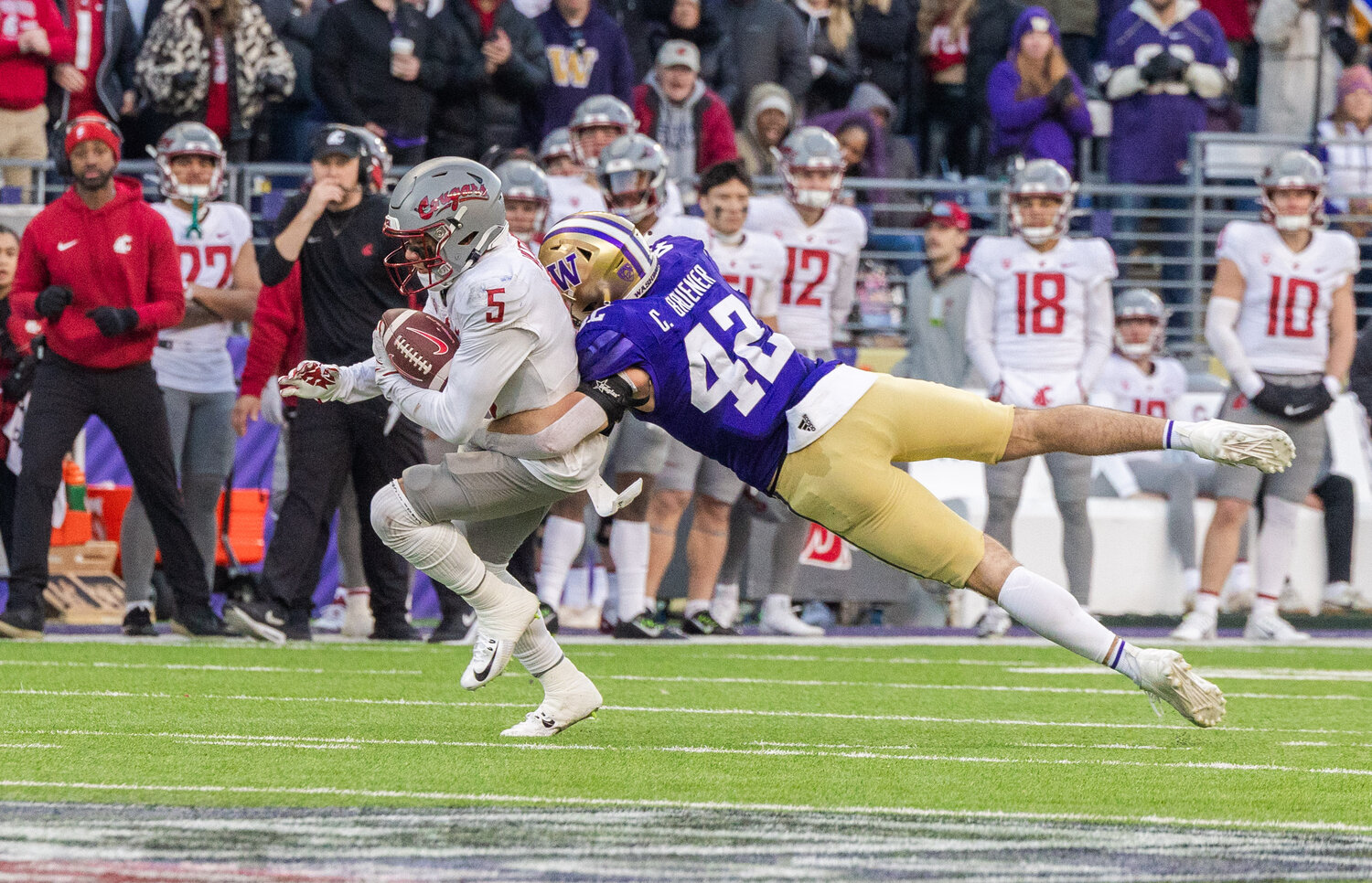 Cougar receiver Lincoln Victor (5) is tackled by Huskies linebacker Carson Bruener (42) during the Boeing Apple Cup Series football game in Seattle on Saturday, Nov. 25.