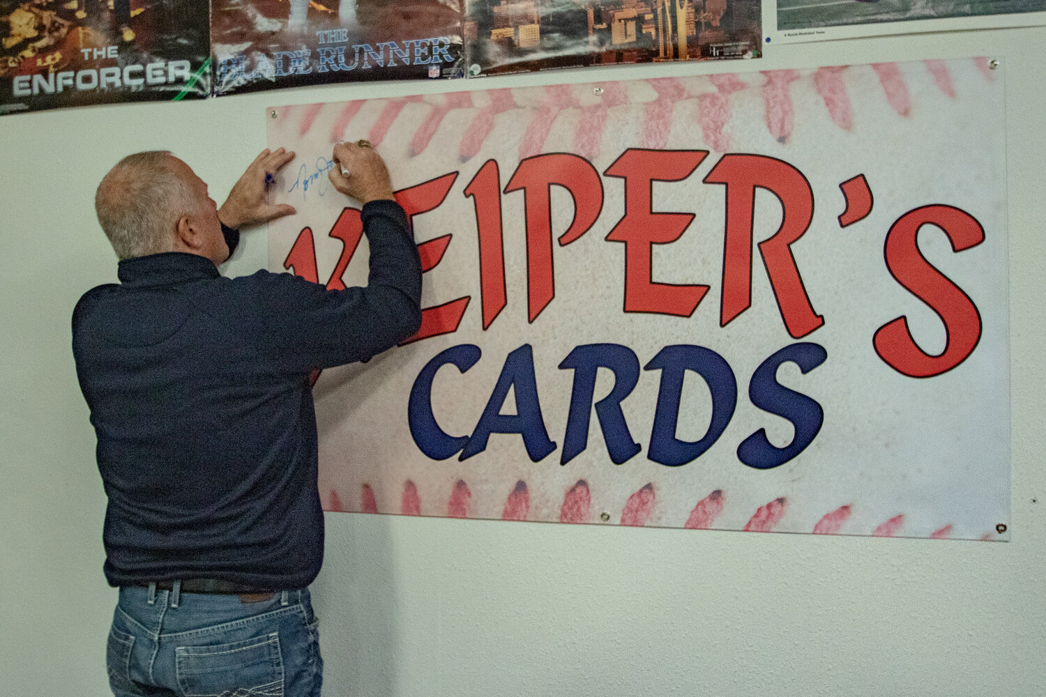 Former Seattle Seahawks kicker Norm Johnson, also known as "Mr. Automatic," signs a banner at Keiper's Cards while appearing to sign autographs for fans at a card and memorabilia show on Saturday, Dec. 2, in downtown Centralia.