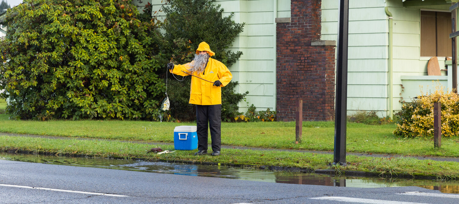 Henry Wegener, dressed as a yellow-clad fisherman, hooks a plastic fish along South Pearl Street in Centralia as water levels began to drop around the Hub City on Thursday, Dec. 7. Wegener said he's "providing for his family" while pointing to his catch but that he's actually just "doing it for the laughs."
